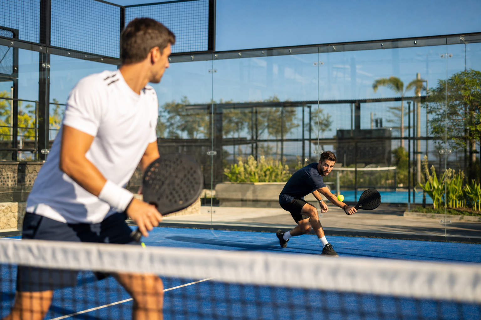 Padel players on an outdoor court in summer sunshine, mid-rally from a defensive back position